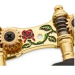 Detalle del grabado decorativo en el Clavijero Alice AOS-028CWP, mostrando un diseño de rosa en color rojo y verde sobre fondo dorado.